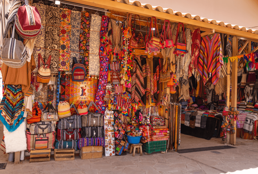 A photo of a stand in a market in Cusco, offering traditional textiles.